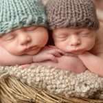 Newborn twins wearing tricot hats and sleeping in a basket