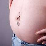 side-view-of-pregnant-belly-with-peircing-picture-id165051430