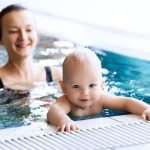 mother-teaching-baby-to-swim-in-a-swimming-pool-picture-id895265892