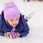 adorable-girl-sitting-on-ice-with-skates-after-the-fall-picture-id477097031