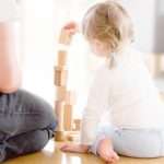 cute-girl-playing-with-wooden-blocks-ont-he-floor-with-her-father-picture-id812660948