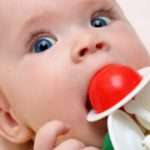 baby girl biting rattle close-up portrait