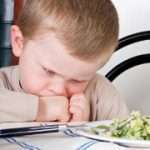 Four year old boy disliking the food on his plate