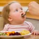 The litle child eats a vegetable salad