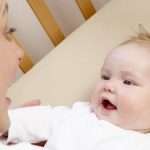 Mother Playing With Baby In Cot