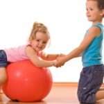 Little firl and boy playing with a large ball on the floor