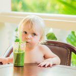 Child drinking healthy green vegetable smoothie – healthy eating, vegan, vegetarian, organic food and drink concept