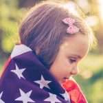 little-girl-outdoors-in-a-meadow-on-july-4th-picture-id506557594