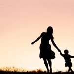 silhouette-of-mother-and-baby-daughter-running-and-dancing-at-sunset-picture-id626866200