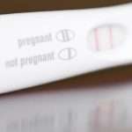 positive-pregnancy-test-closeup-on-a-brown-wooden-table-picture-id115040652