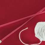 top-view-of-white-wool-ball-and-knitting-needles-isolated-on-red-picture-id917683342