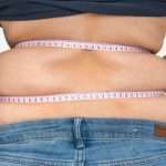 overweight-woman-with-tape-is-measuring-fat-on-belly-picture-id1074826674